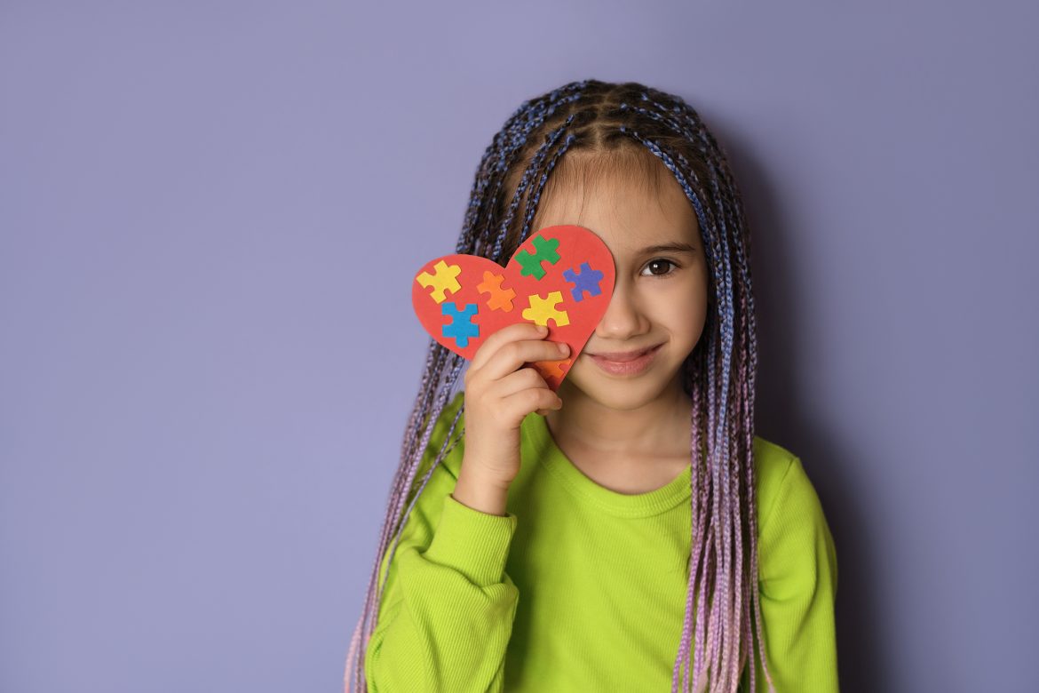 A girl holds a heart with puzzle pieces in her hands